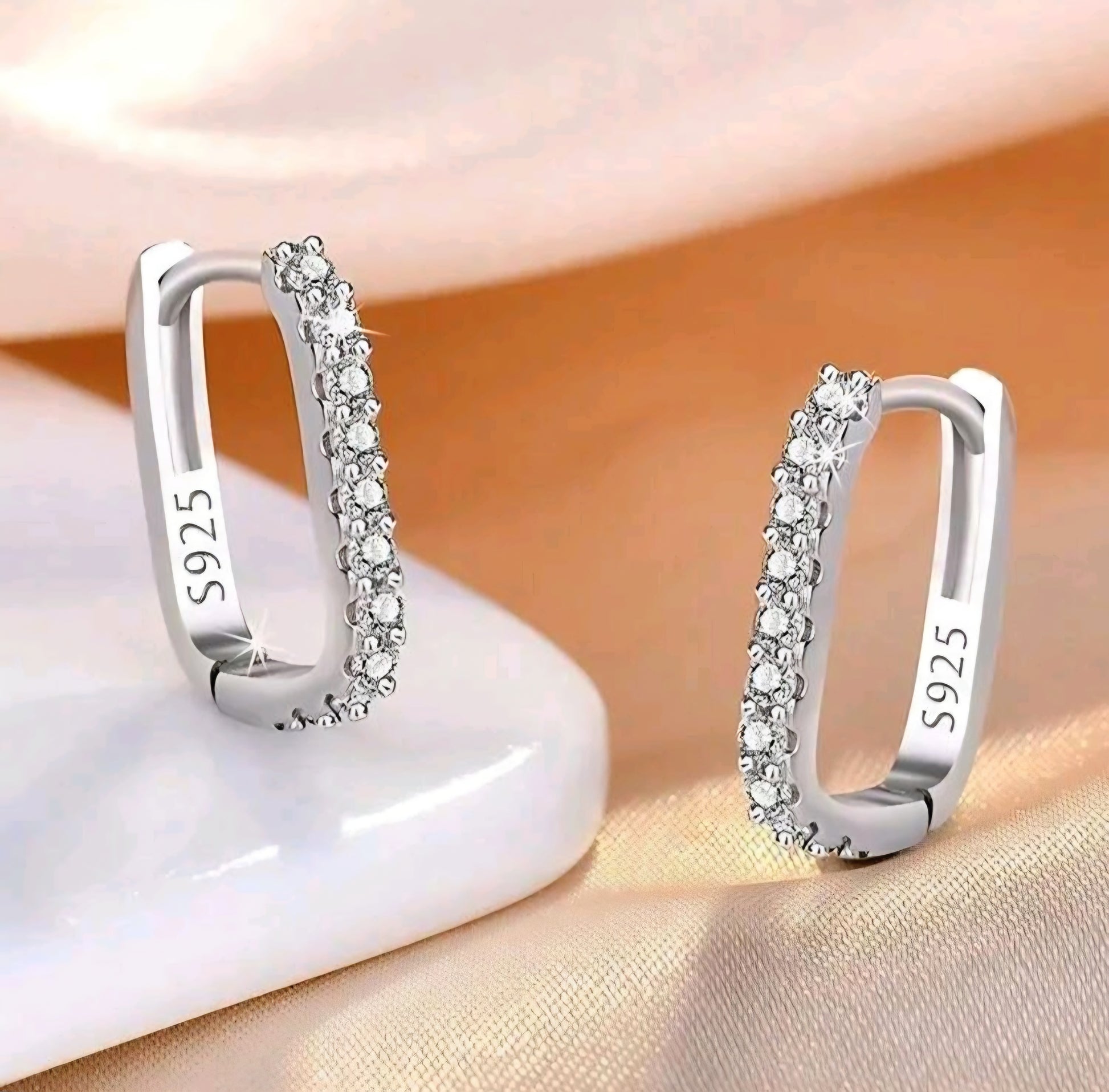 Silver hoop earrings with clear stones on a soft background