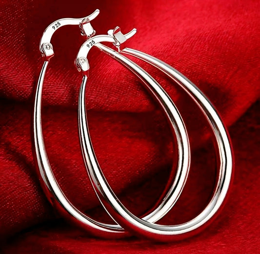 Silver hoop earrings on a red fabric background
