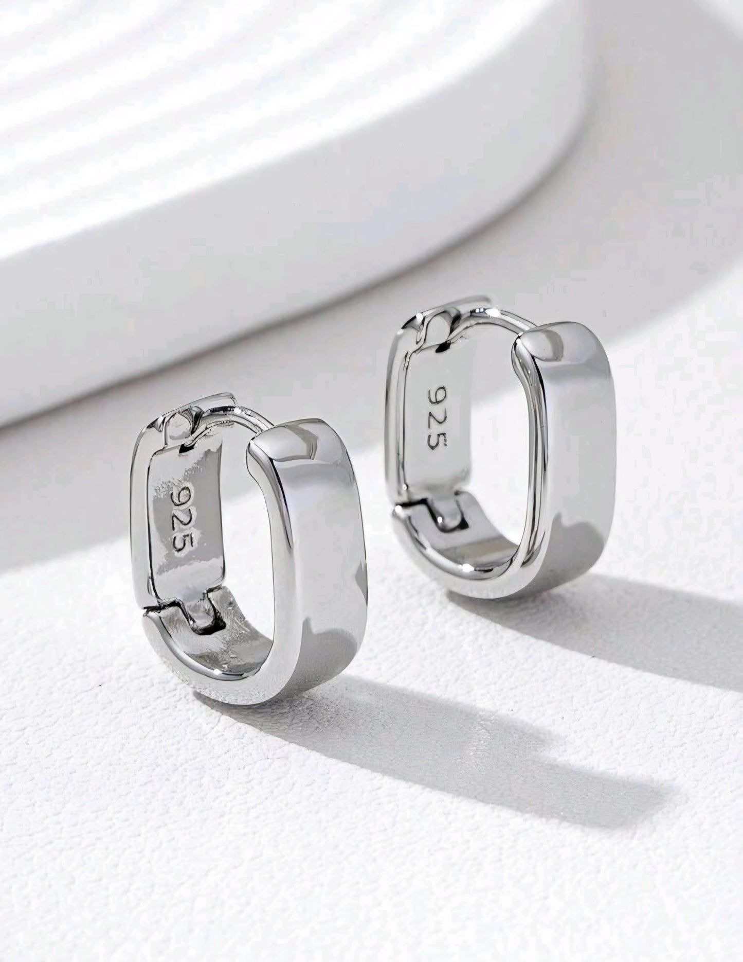 Silver hoop earrings with '925' stamp on a white background
