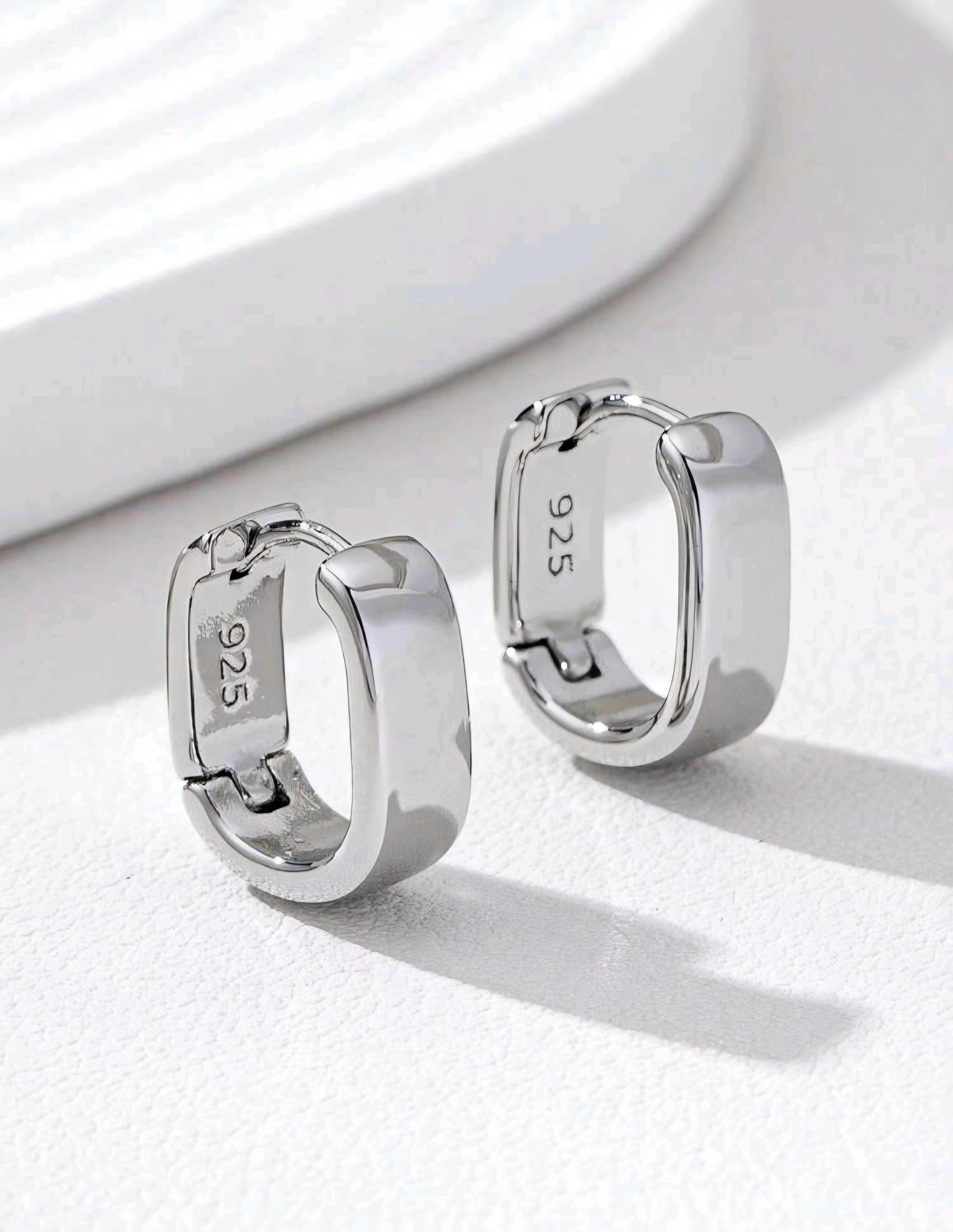 Silver hoop earrings with '925' stamp on a white background