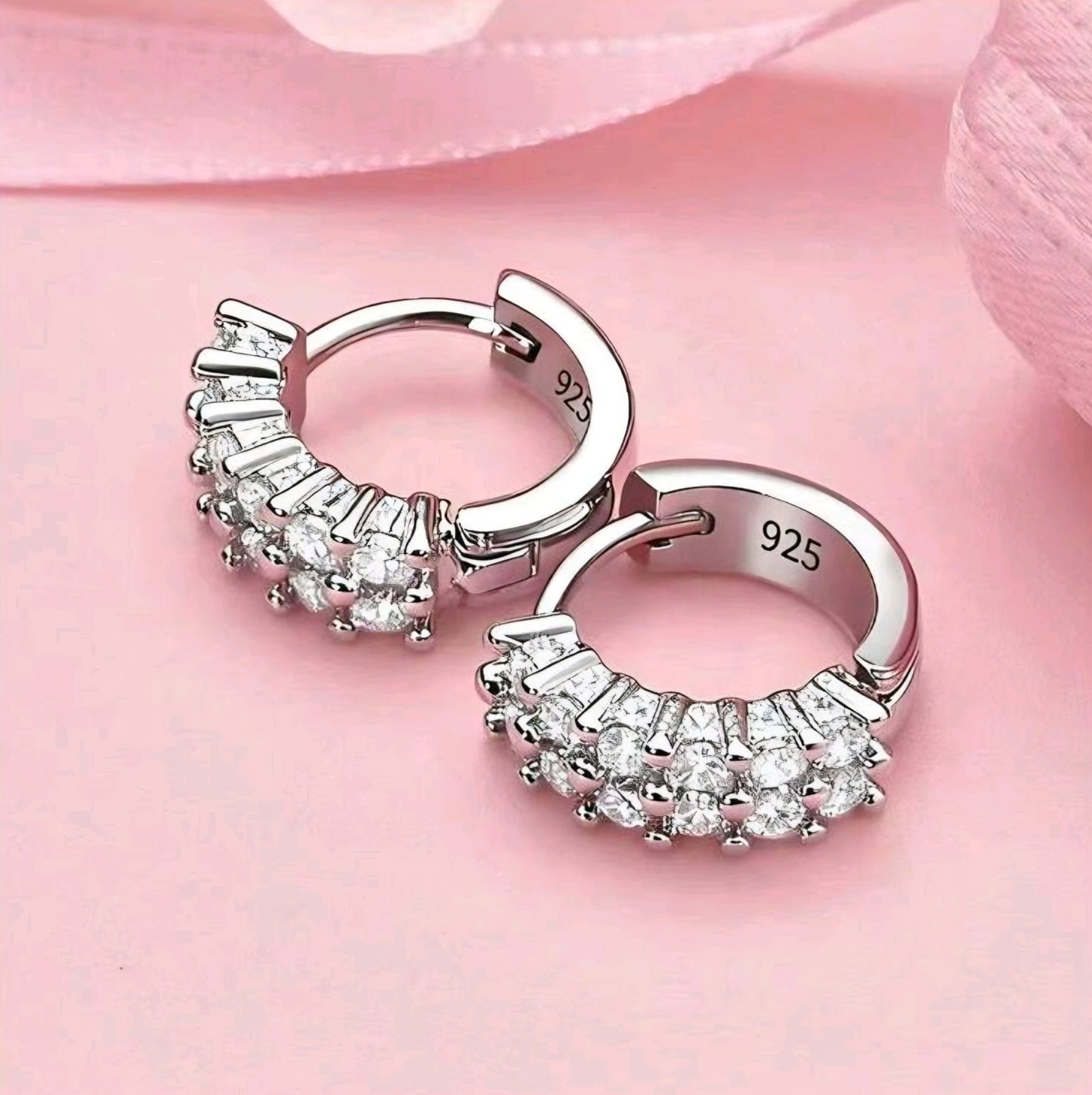Silver hoop earrings with gemstones on a pink background