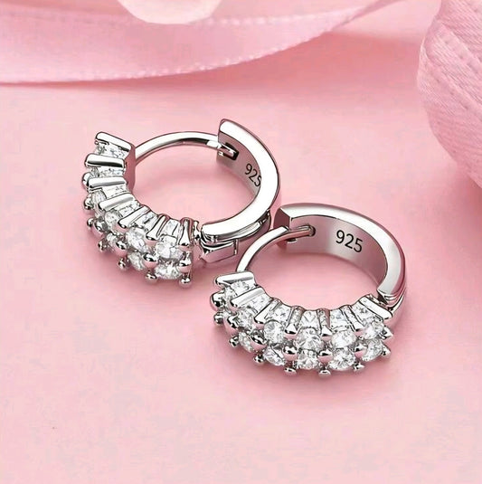 Silver hoop earrings with gemstones on a pink background